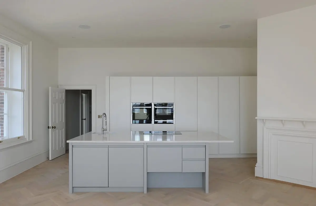 Kitchen in a converted apartment with original fireplace and chevron floor